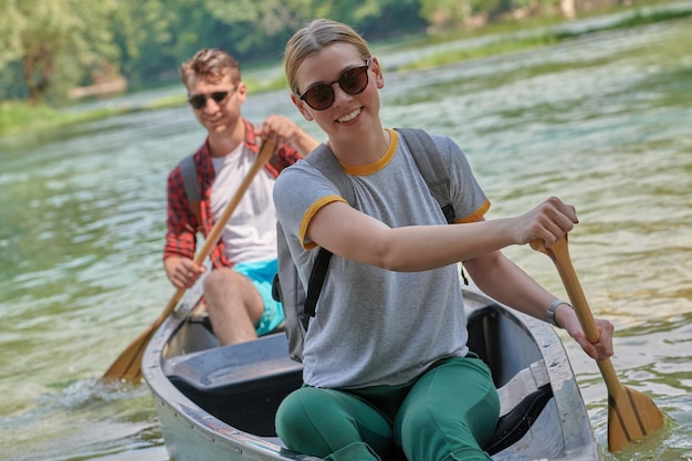 Ein paar abenteuerlustige Entdeckerfreunde fahren in einem wilden Fluss, umgeben von der wunderschönen Natur, Kanu