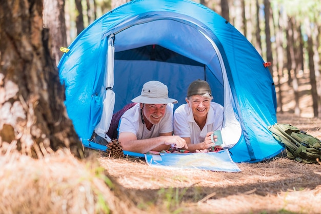 Ein paar aktive reisende Senioren genießen zusammen in einem Zelt beim kostenlosen Camping im Wald