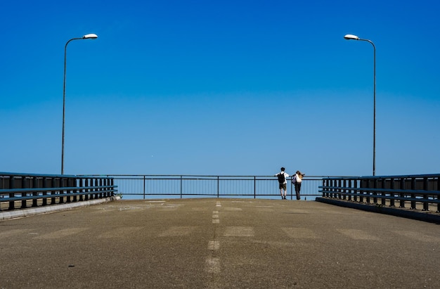 Ein paar am Ende der Stadtbrücke Hintergrund des blauen Himmels Straße zum Himmel