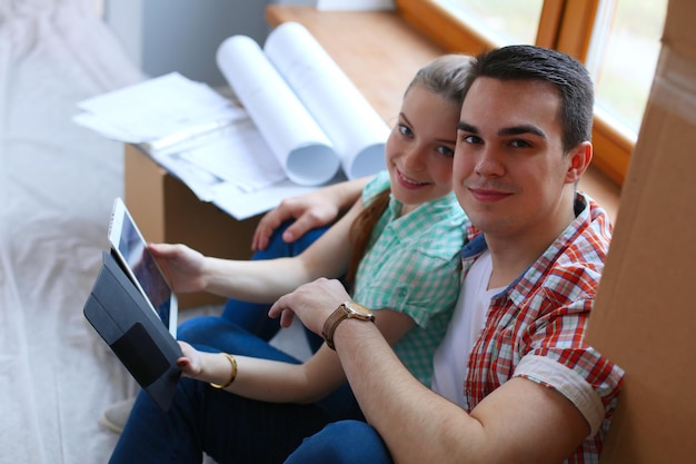 Ein Paar bewegt sich in einem Haus, das mit dem iPad auf dem Boden sitzt Paar