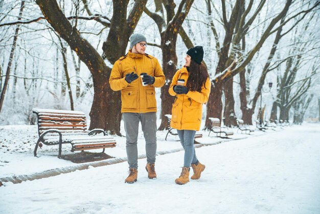 Ein Paar, das durch den verschneiten Stadtpark geht und im Winter über ein romantisches Date spricht