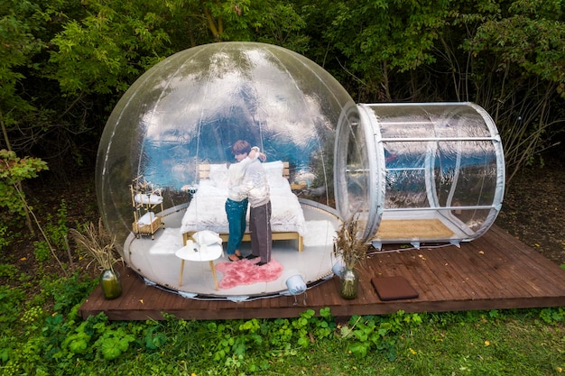 Foto ein paar, das sich beim glamping in einem transparenten blasenzelt umarmt