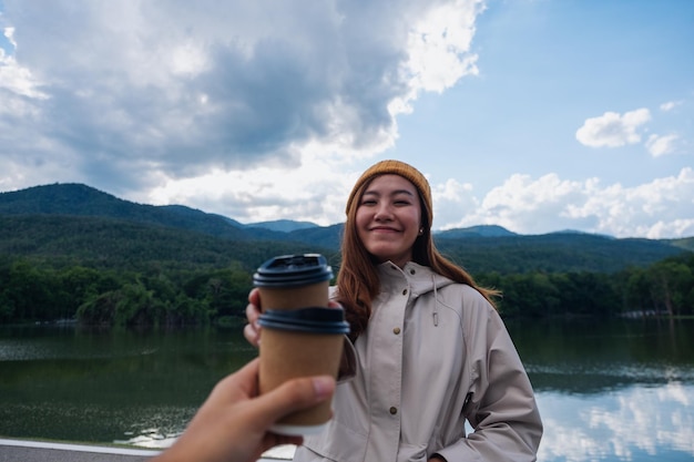 Ein Paar, das zusammen eine Kaffeetasse hält und klirrt, während es Berge und den See bereist