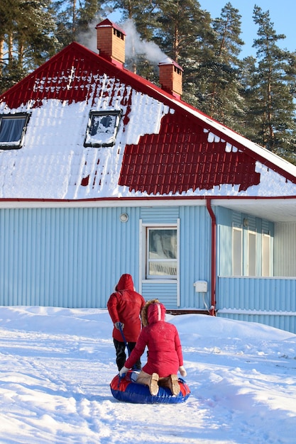 Ein Paar, ein Typ und ein Mädchen mit Winterschläuchen, gehen neben der Hütte spazieren