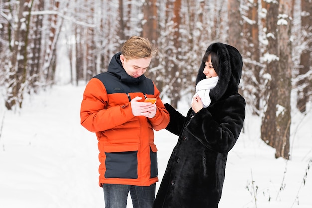 Ein paar Freunde mit einem Smartphone in der Winternatur.