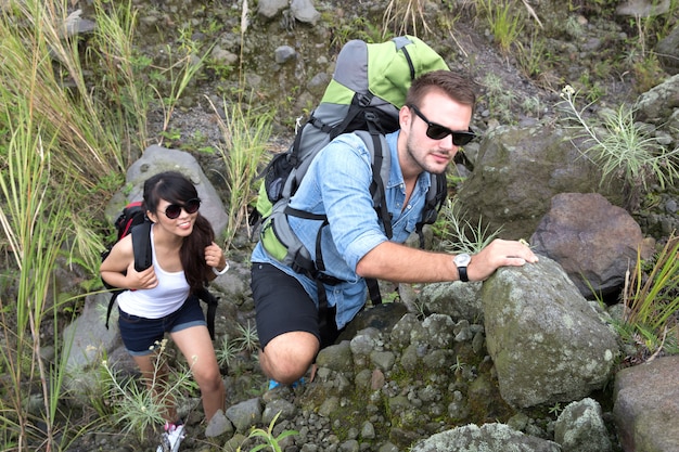 Ein Paar gemischter Rassen geht zusammen wandern und geht bergauf