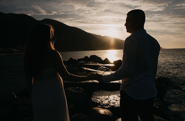 Ein Paar Händchen haltend am Strand bei Sonnenuntergang