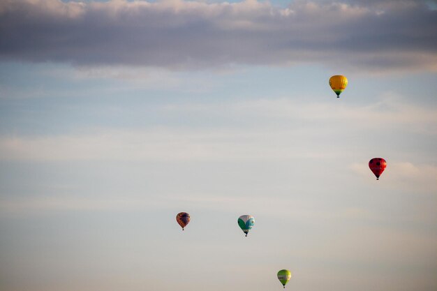 ein paar Heißluftballons fliegen am Himmel.