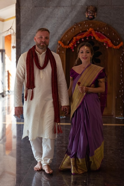 Foto ein paar in einem tempel, das einen sari trägt, und ein mann in einem lila sari