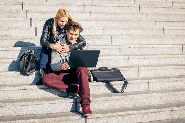 Ein paar junge Hipster-Leute mit Computer-Laptop in urbaner Lage am sonnigen Herbsttag