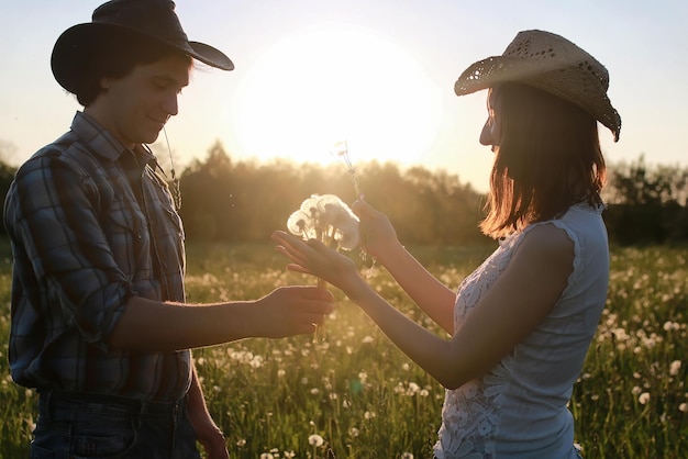 Ein paar junge Leute, die am Sonnenuntergangsfrühlingsabend im Feld spazieren gehen