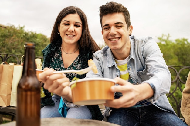 Ein paar junge Leute essen im Freien auf plastikfreien Papierschüsseln