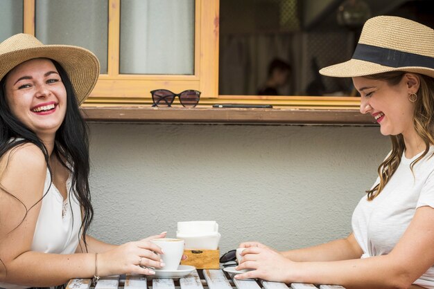 Ein paar junge und glückliche kaukasische Mädchen haben Spaß beim Lachen und machen eine Kaffeepause in der Bar im Freien - fröhliche Frauen in Freundschaft oder Beziehung genießen ihre Freizeit