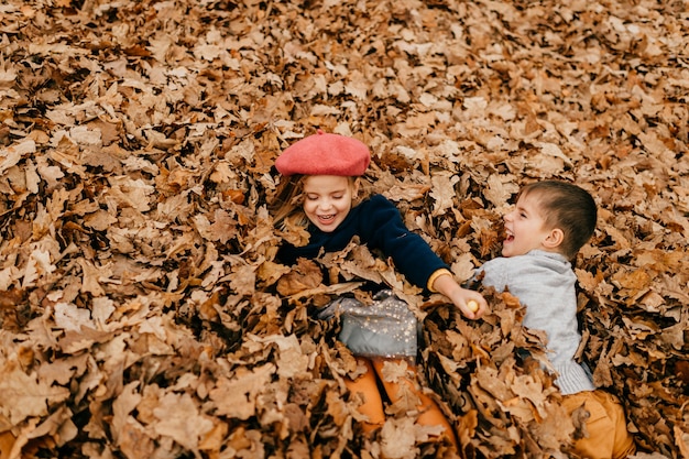 Ein paar Kinder spielen in Blättern