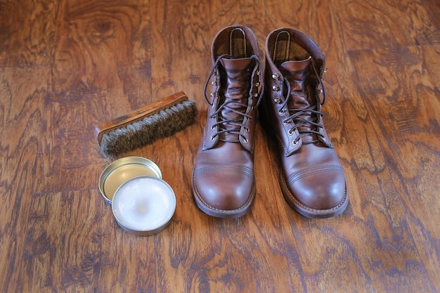 Ein Paar Lederschuhe für Herren braune Boors, eine Schuhbürste und Schuhcreme, Nerzfett auf einem Holzboden