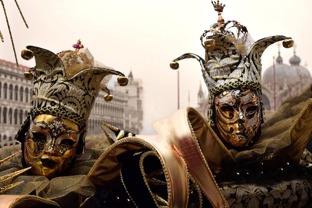 Ein paar Leute, die sich für den Karneval in Venedig verkleidet haben und goldene und schwarze Harlekinkostüme tragen