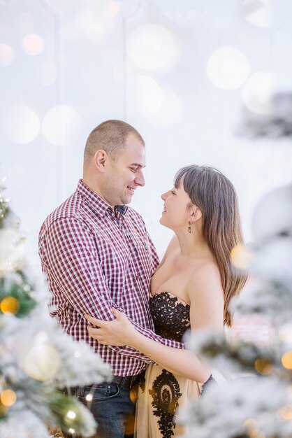 Ein Paar mittleren Alters in schicker Kleidung gegen einen Weihnachtsschneebaum