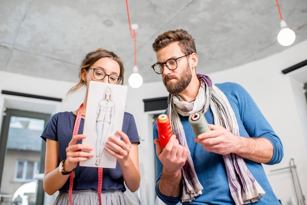 Ein paar Modedesigner, die im Studio mit Kleidungsskizzen arbeiten