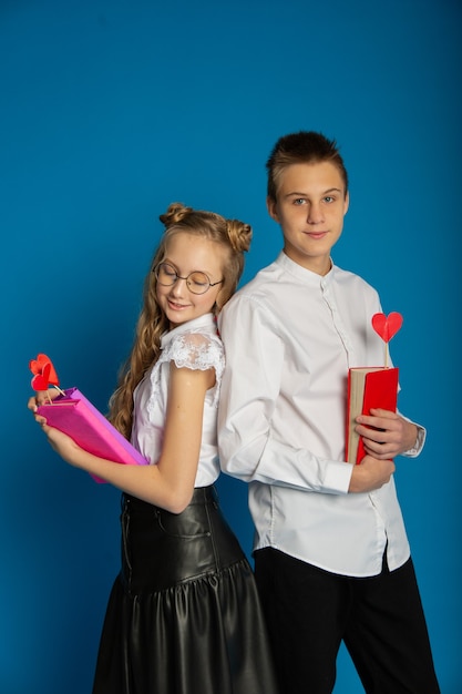 Ein paar Schulkinder sind Teenager am Valentinstag auf blauem Grund