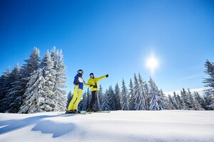 Ein paar skifahrer auf skiern auf dem hügel im skigebiet. freizeitaktivitäten im bergkonzept. low-winkel-aufnahme in voller länge