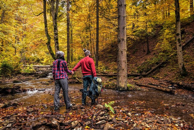 Ein paar Touristen, die im Herbstwald spazieren gehen