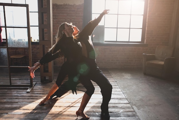 Ein Paar von zwei professionellen Ballsaaltänzern tanzt auf dem Loft-Studio Schöne Kunstperformance Sportlebenskonzept Leidenschaft und emotionaler Tanz