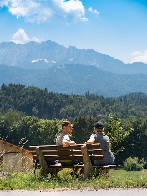 Ein Pärchen sitzt auf einer Bank und genießt eine schöne Aussicht auf die Alpen