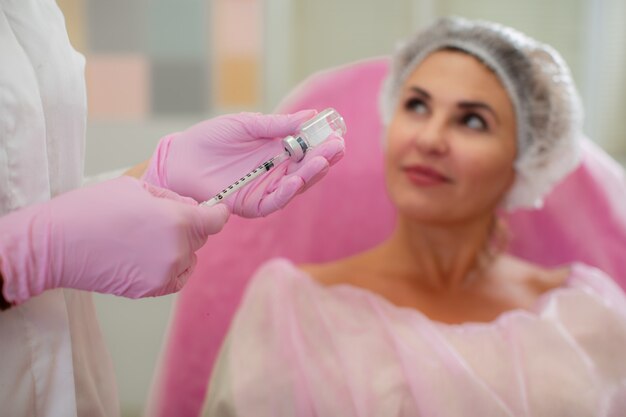 Ein Patient in einer Kosmetikklinik mit einer Einwegkappe sieht den Arzt schlau an