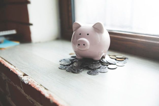 Foto ein piggybank sitzt auf einem tisch vor einem fenster