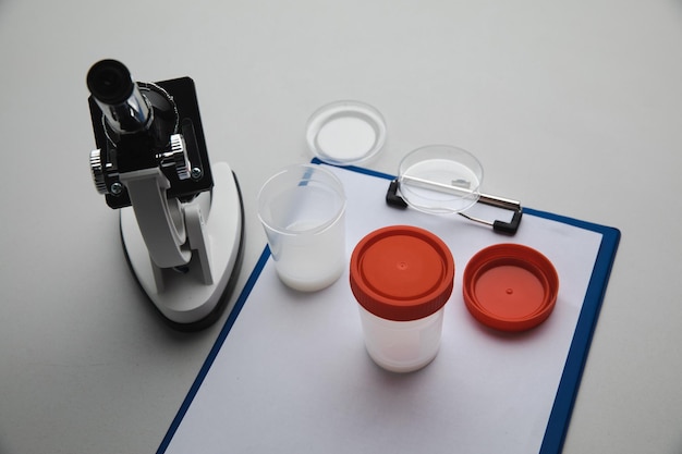 Ein Plastikglas mit Spermien und Mikroskop im Labor Schwangerschaftsvorsorge und Analysekonzept