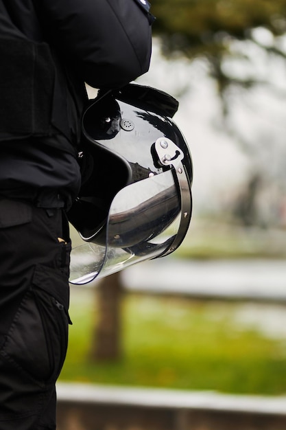 Ein Polizist in schwarzer Uniform mit Schutzhelm auf der Brust bei Demonstration