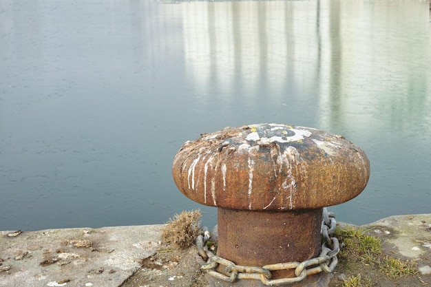 Ein Pollerhafen an einem Hafen Rusty Mooring Poller aus Gusseisen am Pierufer Himmel und Wasser im Hintergrund Copyspace Sicherung des Ankerpunkts, um zu verhindern, dass Schiffe aufgrund von Gezeitenstrom und Wind abdriften