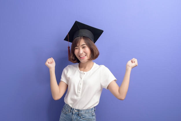 Ein Porträt des jungen asiatischen Studenten, der Abschlusskappe über Studiohintergrund trägt.