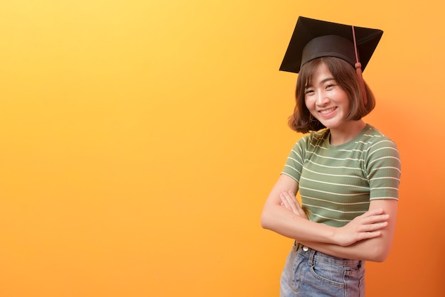 Ein Porträt des jungen asiatischen Studenten, der Abschlusskappe über trägt