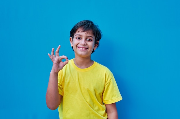 Ein Porträt des Jungen im gelben T-Shirt, das ok Geste mit der Hand macht