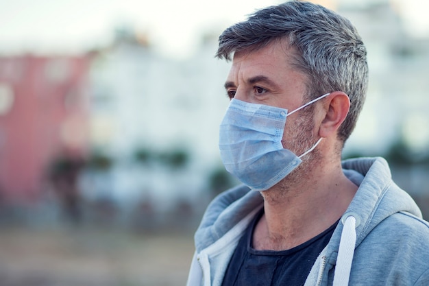 Ein Porträt des Mannes mit der medizinischen Gesichtsmaske im Freien. Konzept für Menschen, Gesundheitswesen und Medizin