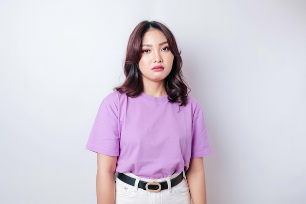 Ein Porträt einer asiatischen Frau, die ein lila lila T-Shirt trägt, das von weißem Hintergrund isoliert ist, sieht deprimiert aus