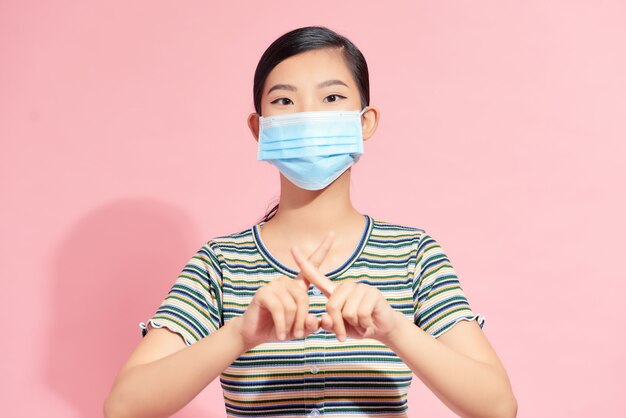 Ein Porträt einer Frau mit medizinischer Gesichtsmaske, die Stoppgeste zeigt. Konzept für Menschen, Gesundheitswesen und Medizin