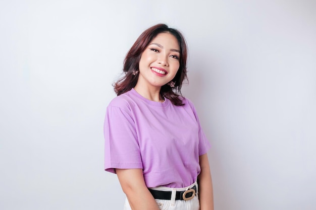 Ein Porträt einer glücklichen asiatischen Frau, die ein lila lila T-Shirt trägt, das von weißem Hintergrund isoliert ist