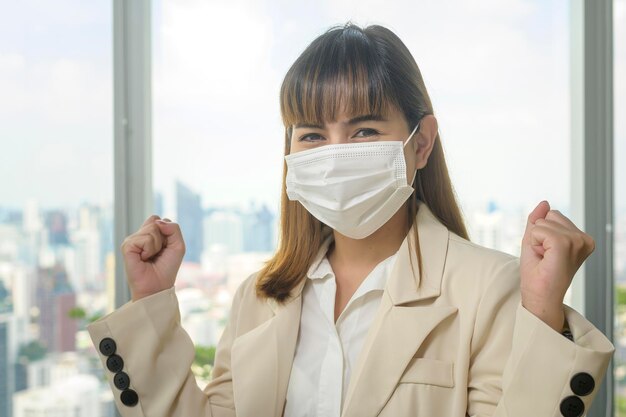 Ein Porträt einer jungen schönen Geschäftsfrau, die eine Schutzmaske im modernen Büro trägt
