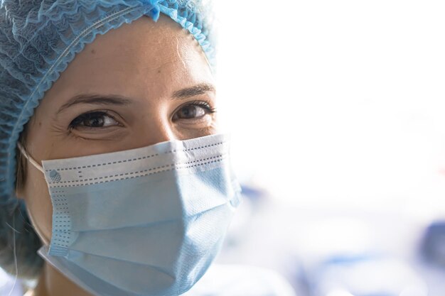 Ein Porträt einer weiblichen Ärztin, die eine Gesichtsmaske und eine Kappe für die chirurgische Arbeit der Patienten trägt
