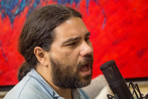 Foto ein porträt eines bärtigen hispanischen mannes vor einem mikrofon.