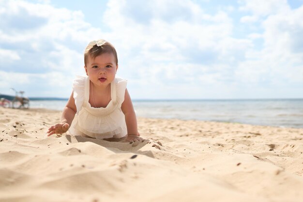 Ein Porträt eines einjährigen kaukasischen Babys am Sandstrand an einem sonnigen warmen Tag am Ostsee