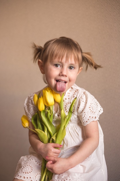 Ein Porträt eines schönen kleinen Mädchens mit einem Strauß gelber Tulpenblumen