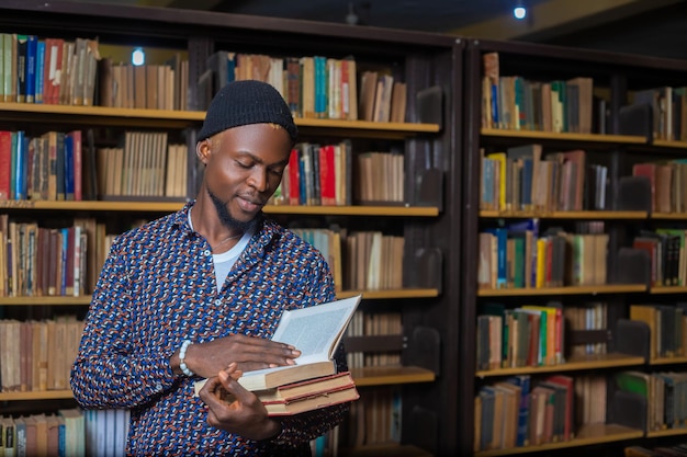 Ein Porträt eines schwarzen College-Studenten-Mannes in der Bibliothek. Geringe Schärfentiefe