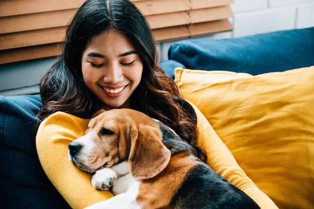 Ein Porträt von Glück und Bindung. Eine Frau und ihr Beagle-Hund schlafen zusammen auf dem Sofa im Wohnzimmer und verkörpern das Konzept der besten Freunde für immer und die Freude der Gemeinschaft.