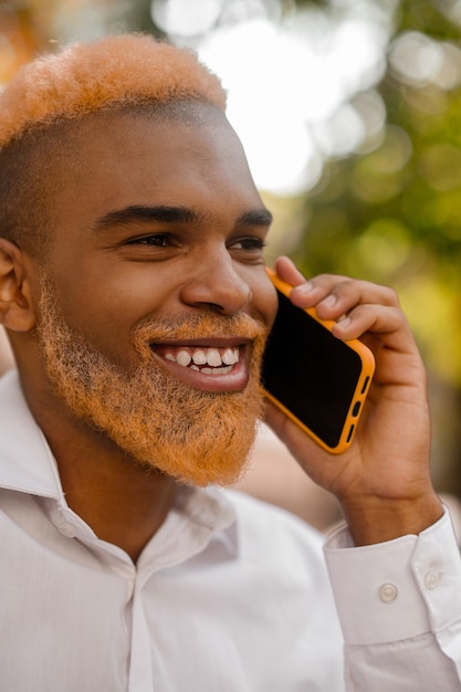 Ein positiv gutaussehender stylischer Mann mit einem Smartphone