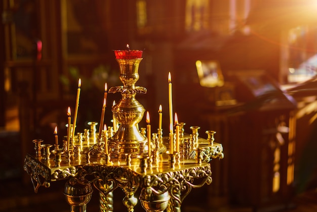 Ein Prachtboden-Kirchenkerzenhalter mit brennenden Kerzen schoss Nahaufnahme auf dunklem Hintergrund...