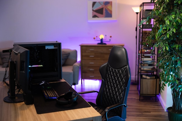 Ein professioneller computer mit hintergrundbeleuchtung für einen gamer, der monitor steht auf einem schreibtisch im gemütlichen zimmer