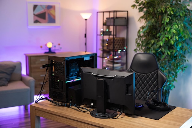Ein professioneller Computer mit Hintergrundbeleuchtung für einen Gamer, der Monitor steht auf einem Schreibtisch im gemütlichen Zimmer